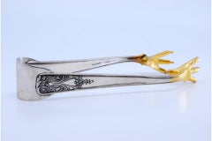 Silver ice tongs in the shape of golden claws with reliefs on the handles