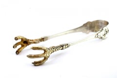 Silver ice tongs with gold claws, raised temples and grooves along the length