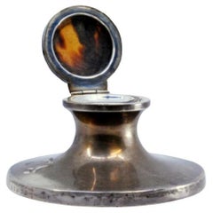 Silver inkwell w/ wooden base 
smooth body w/ tortoiseshell elements on the lid