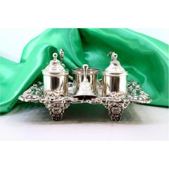 Silver inkwell with floral cutouts, two reservoirs, bell & relief feet
