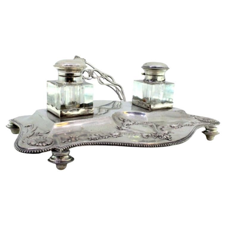 Silver inkwell with two glass tanks on a base with floral reliefs on four feet