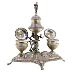 Silver inkwell with two tanks, Putti bell support 
cut-out feet