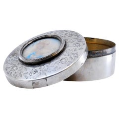 Portagioie in argento con motivi vegetali incisi che circondano un'antica signora