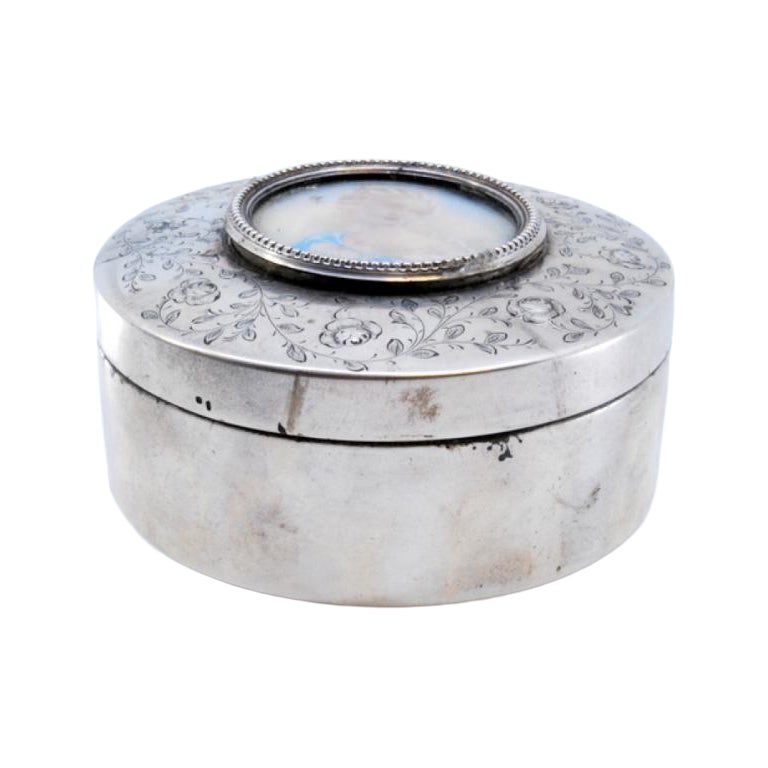 Silver jewelry box with engraved plant motifs surrounding an ancient lady