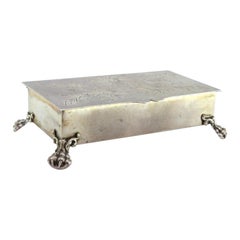 Silberne Schmuckschatulle mit floralen Deckelgravuren und vier klauenförmigen Füßen