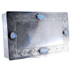 Silver jewelry box with plant engravings and colored stones on lid