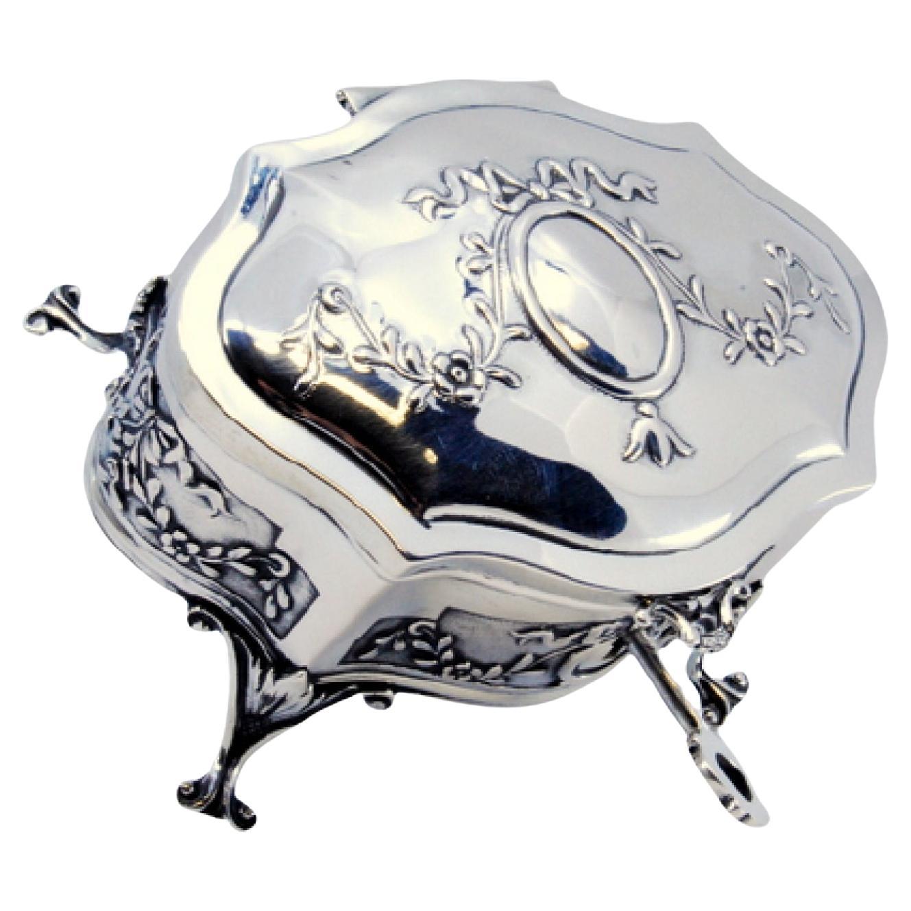 Boîte à bijoux en argent avec rubans, monogramme et quatre supports de pieds de palmier.