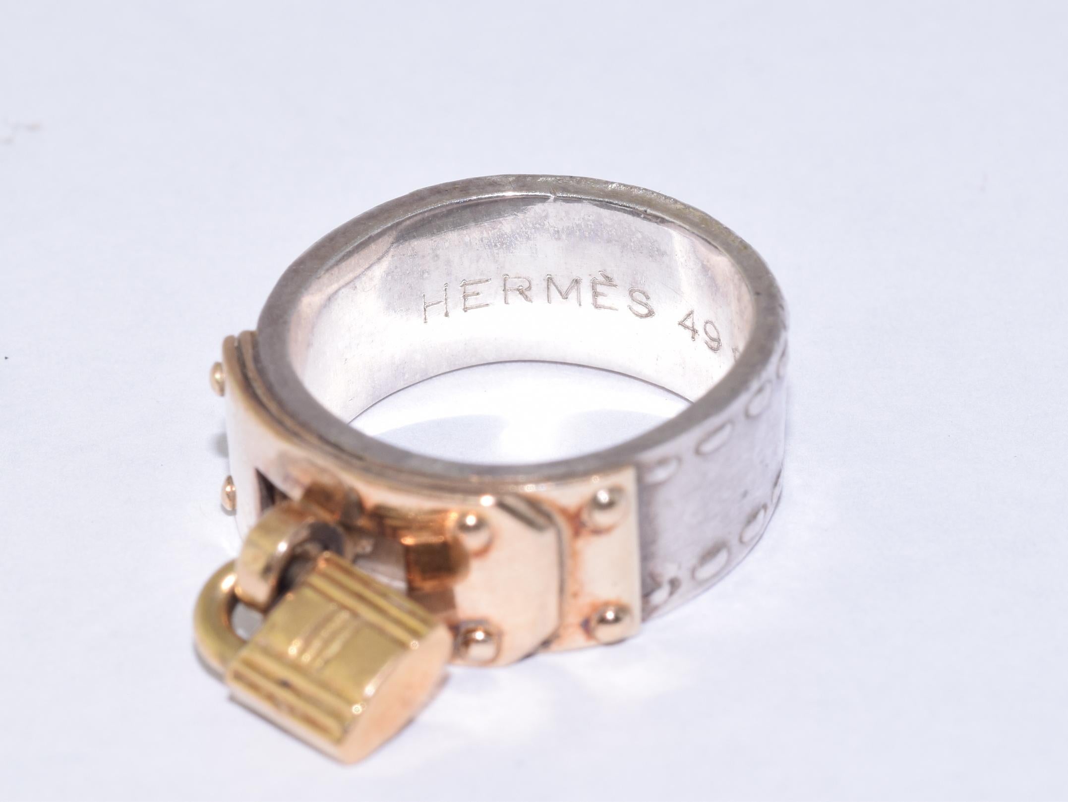 A silver band with yellow gold panel and padlock is signed Hermes. Finger size 4.75. Width: approx.  7.74mm.