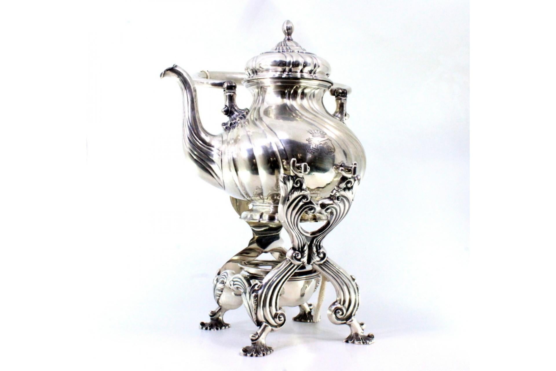 Description : Bouilloire en argent à reliefs cannelés, bouton sur le couvercle, reposant sur une structure avec une lampe et quatre pieds surélevés. Métal : Argent. Origine : Allemand. Marque : Inconnu. Poids : 1927,51 grammes. Dimensions :