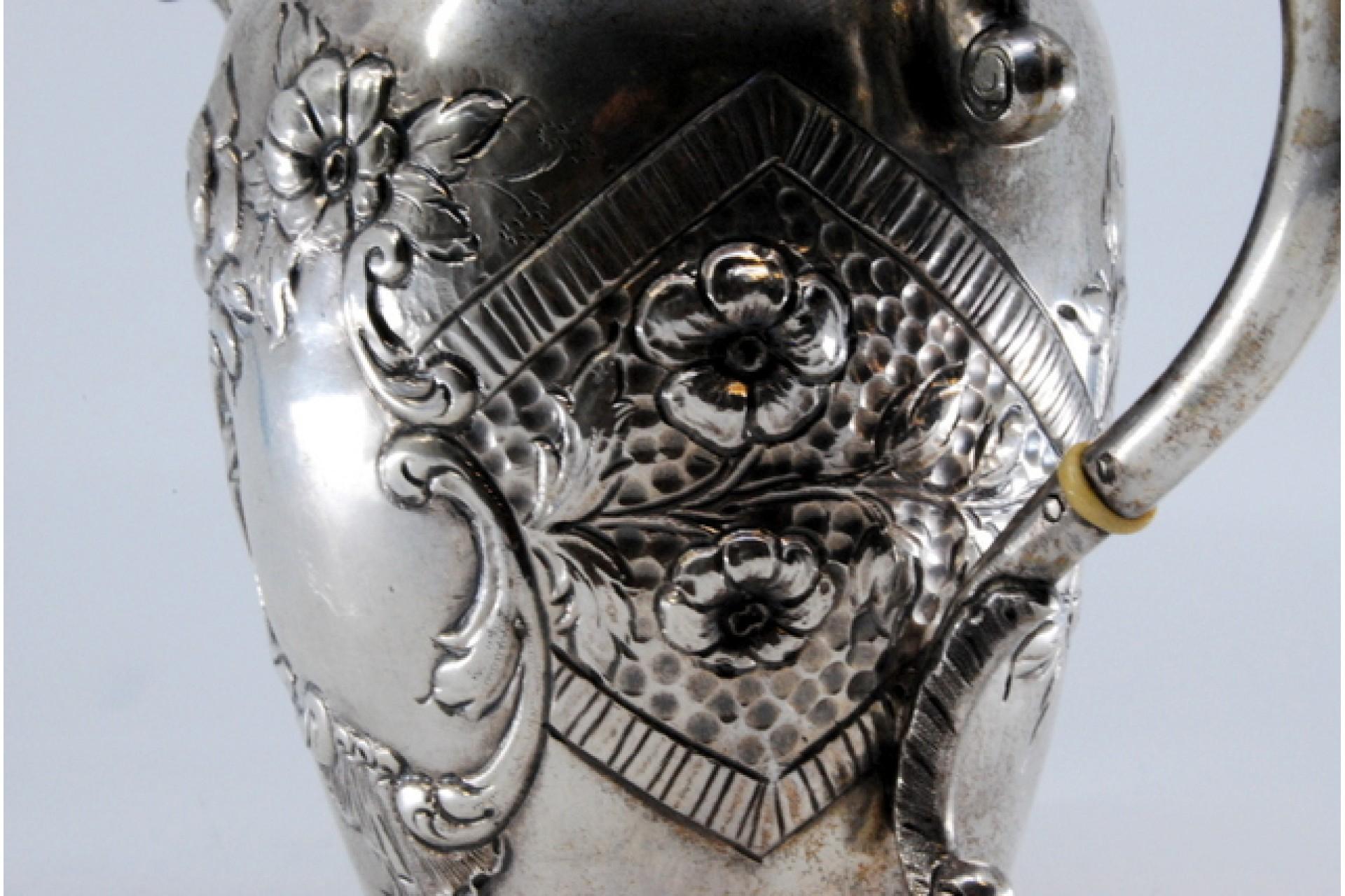 Description : Bouilloire en argent avec des reliefs et sur la poignée du couvercle amovible. Métal : Argent. Origine : Portugais. Poinçon : aigle debout. Poids : 338,91 grammes. Dimensions : 15x5,3cm : 15x5,3cm. Contenu : 833/1000. Marque d'essai :