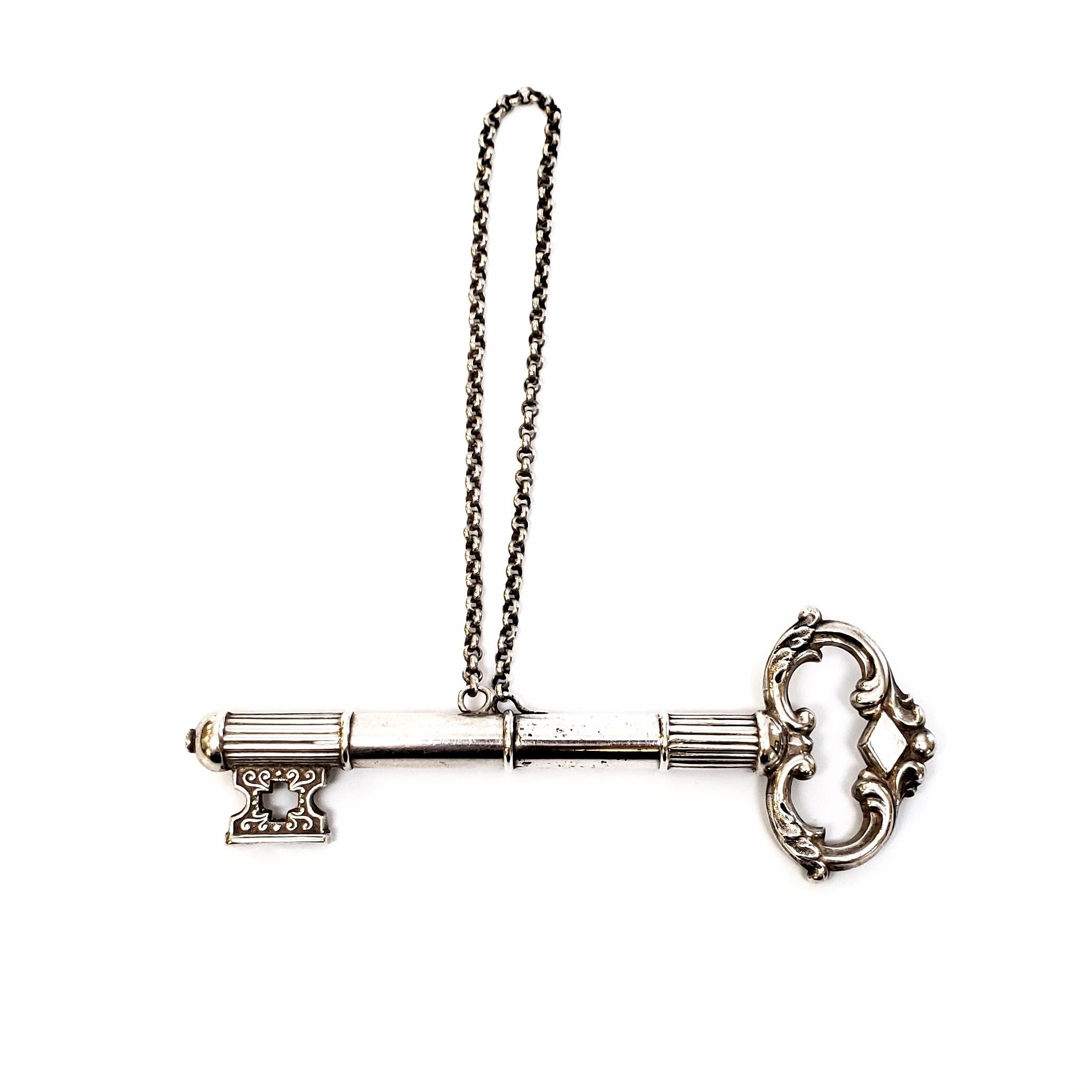 Antique silver key needle case with chatelaine chain.

The case turns in the middle to open and lock. Simple but elegant scroll design.

Measures: 4 1/4