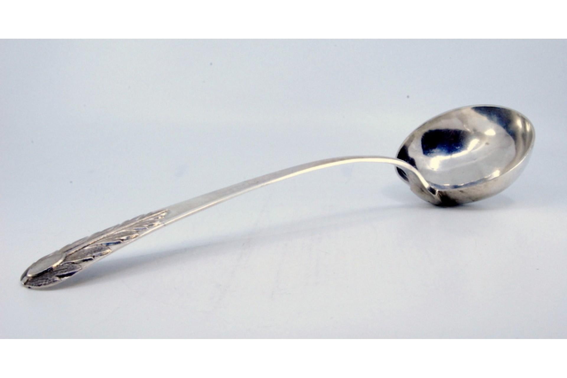 Description: Silver soup ladle with embossed acanthus leaf on the handle and monogram cartouche. Metal: Silver. Origin: Portuguese. Brand: Porto Coroa. Weight: 231.82 grams. Dimensions: 32x9.3cm. Content: 833/1000. Assay Mark: Yes, from the 15th
