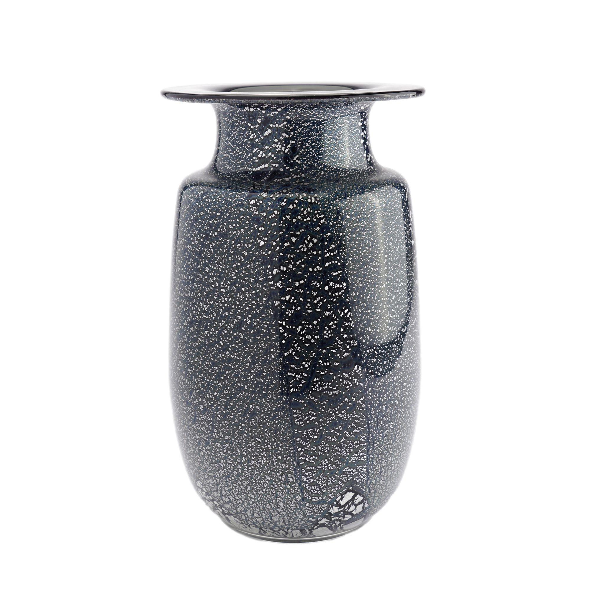 Mouth blown case glass art vase with a waisted standing rim below a flaring lip. The deep slate blue/black glass is infused with silver leaf flecks and encased in clear glass. The underfoot has a ground and polished pontil. 
Murano, Venice, Italy,