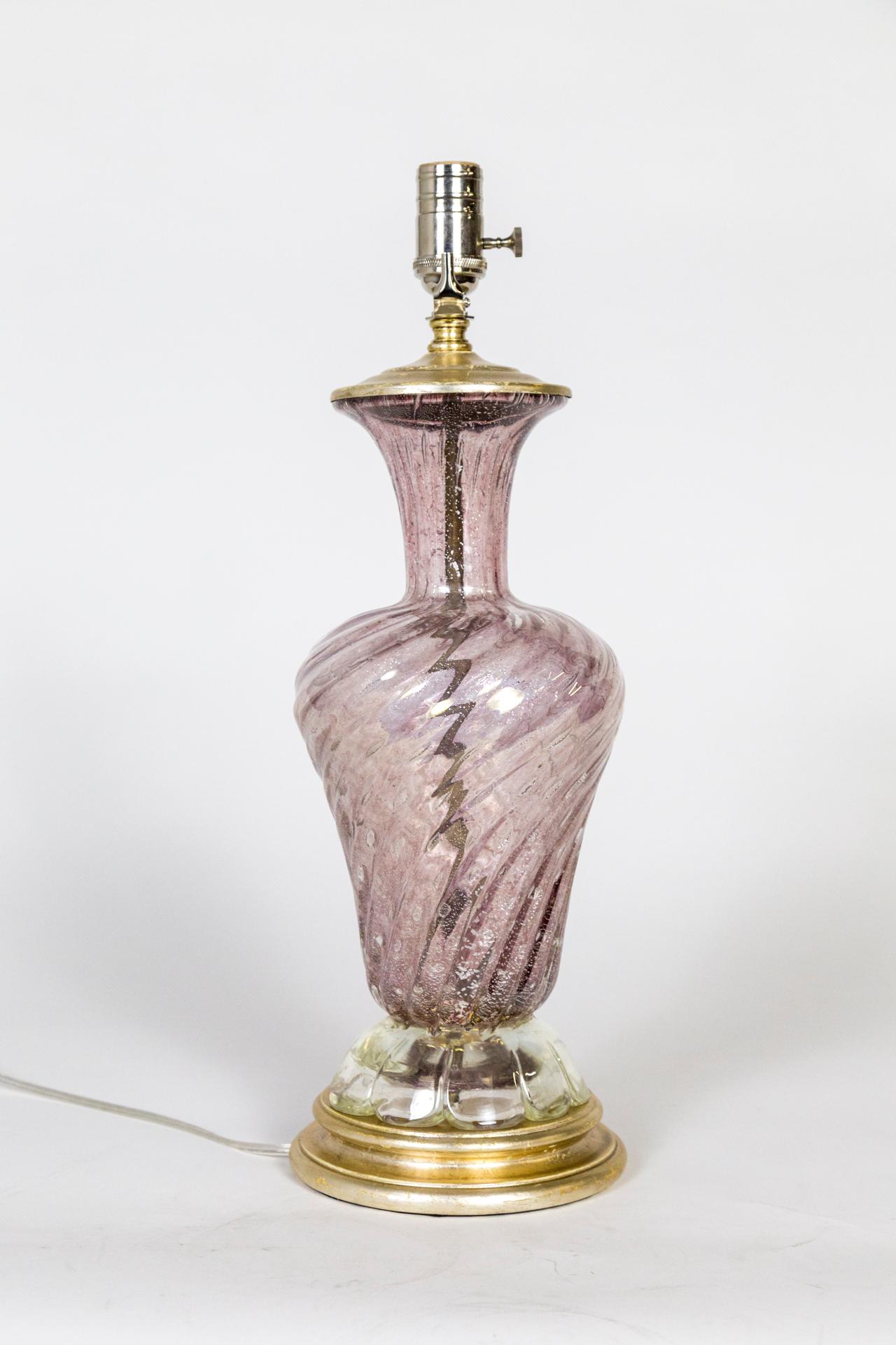 Lampe en verre de Murano en forme d'urne tourbillonnante avec fond festonné, de couleur rose poussiéreuse transparente avec des mouchetures d'argent ; base et capuchon dorés à l'argent. Quincaillerie en nickel poli, dorure à la feuille d'argent