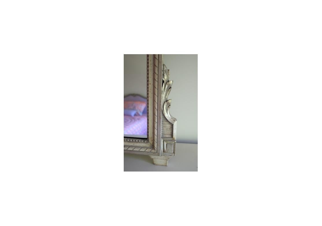 A large and very decorative mirror with parcel gilt frame, ribbons and bows. Beautiful ribbon and tassel surround an oval crest with painted rose over mirror.

Dimensions: 39 1/4