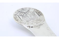 Tagliacarte in argento con moneta in rilievo sulla parte superiore e croce sulla lama.