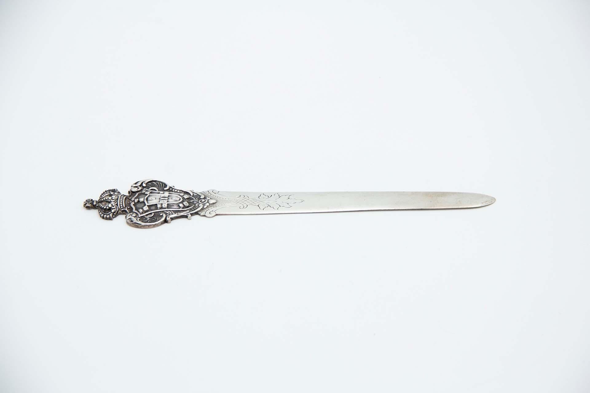 Descripción: Abrecartas de plata con el escudo de Portugal grabado en la hoja. 
Metal: Silver. 
Origen: Portugués. 
Marca: boar II Título. 
Peso: 57,38 gramos. 
Dimensiones: 22cmx0,5cm. 
Contenido: 833/1000. 
Marca de ensaye: Sí, entre 1887 y 1937.