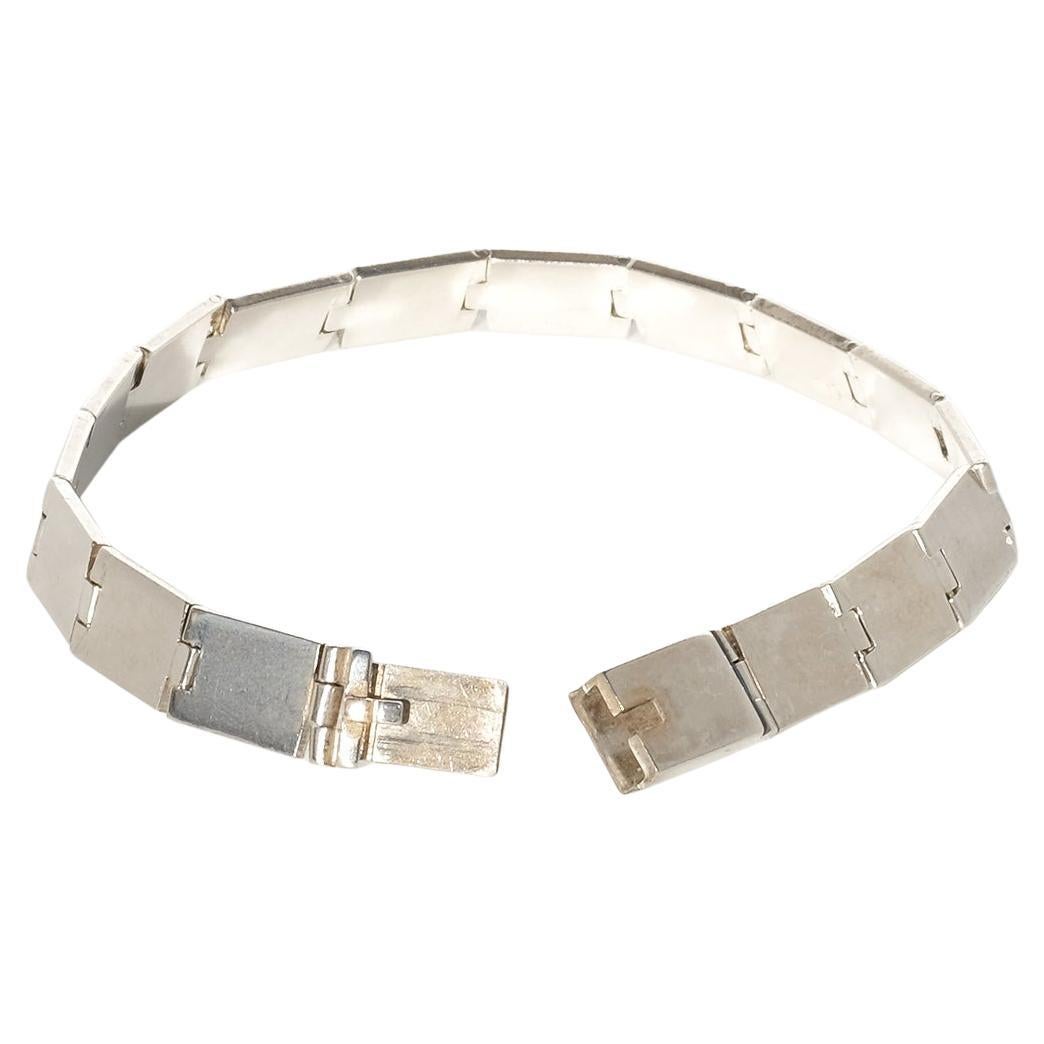 Dieses Silberarmband besteht aus flachen, rechteckigen Gliedern, die durch diskrete Scharniere miteinander verbunden sind, so dass sich jedes Glied reibungslos bewegen lässt. Die Glieder sind in einer durchgehenden, flexiblen Linie angeordnet und