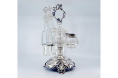 Silver liqueur bottle with floral motifs, mascaron feet, and spice deposits