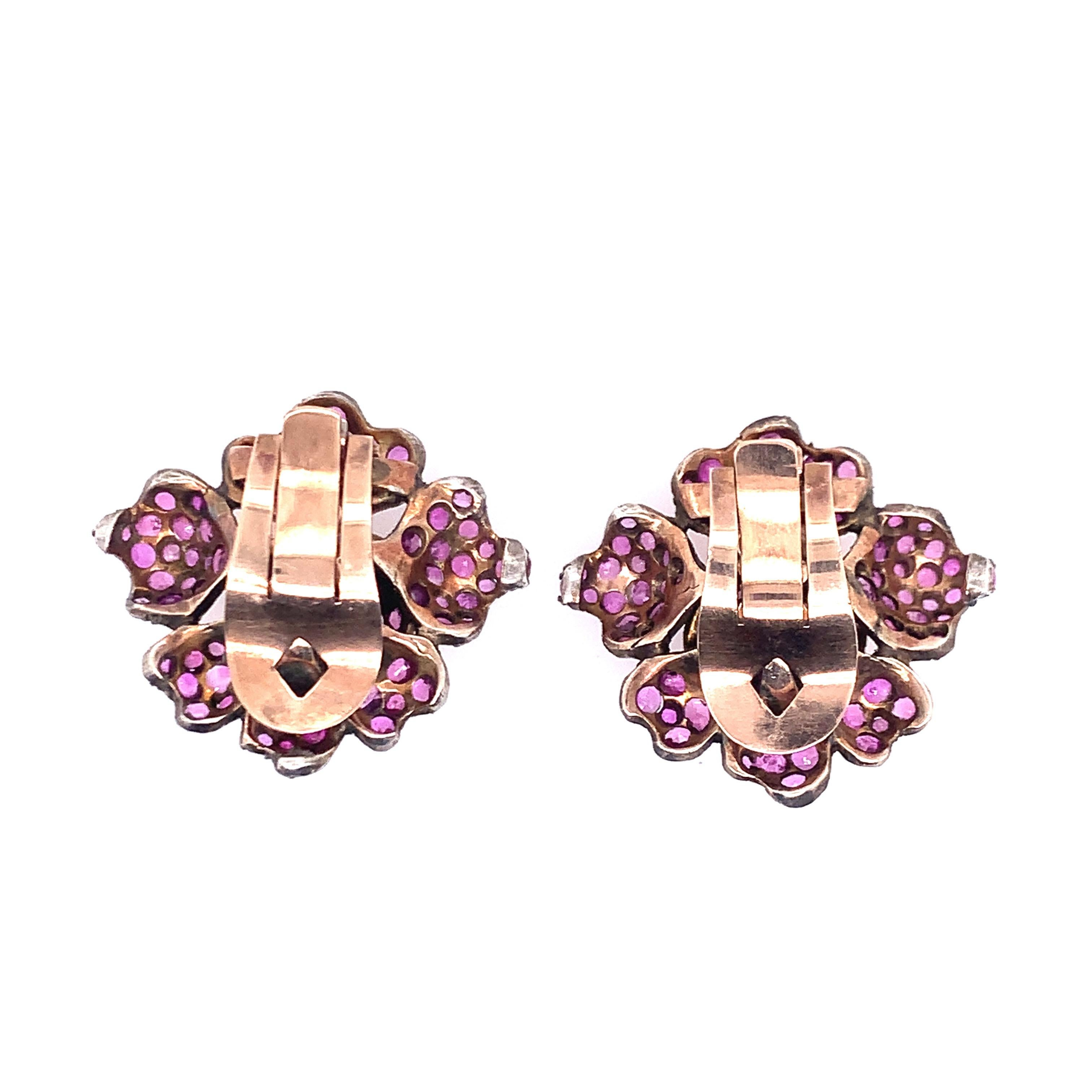 A pair of floral ear clips adorned with round rubies, weighing 15.3 grams. 

 
