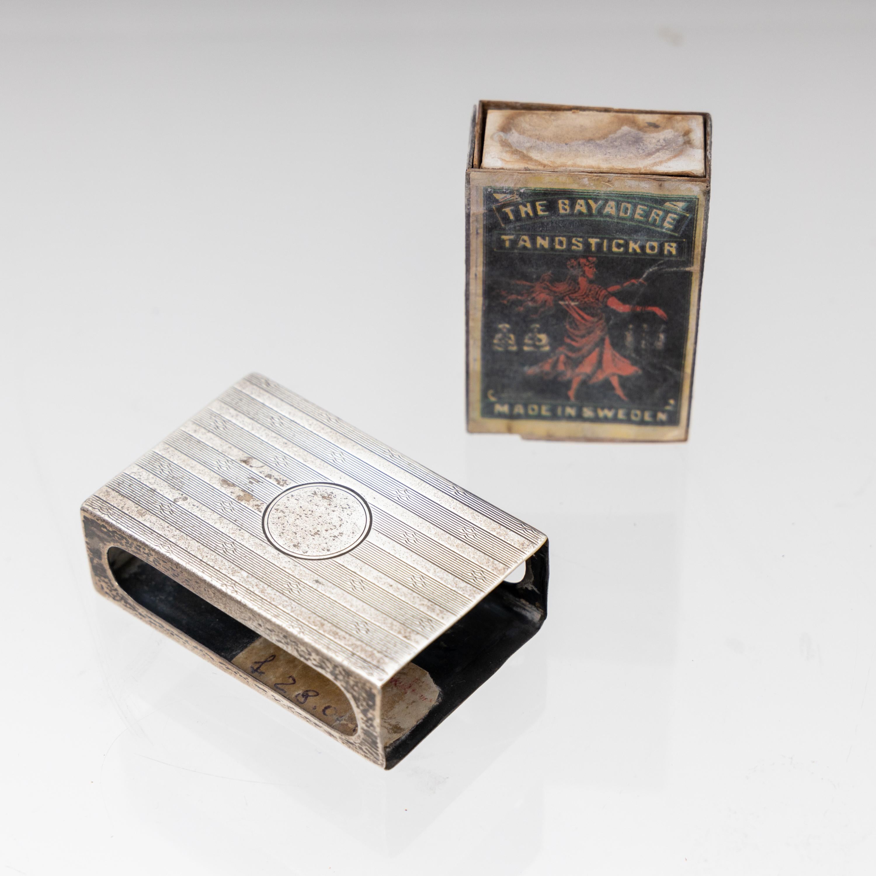 English matchstick case made of silver, stamped on the bottom and match box made of paper.