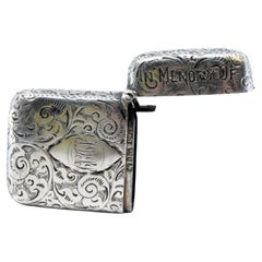 Silver matchstick with relief plant motifs surrounding monogram cartouche