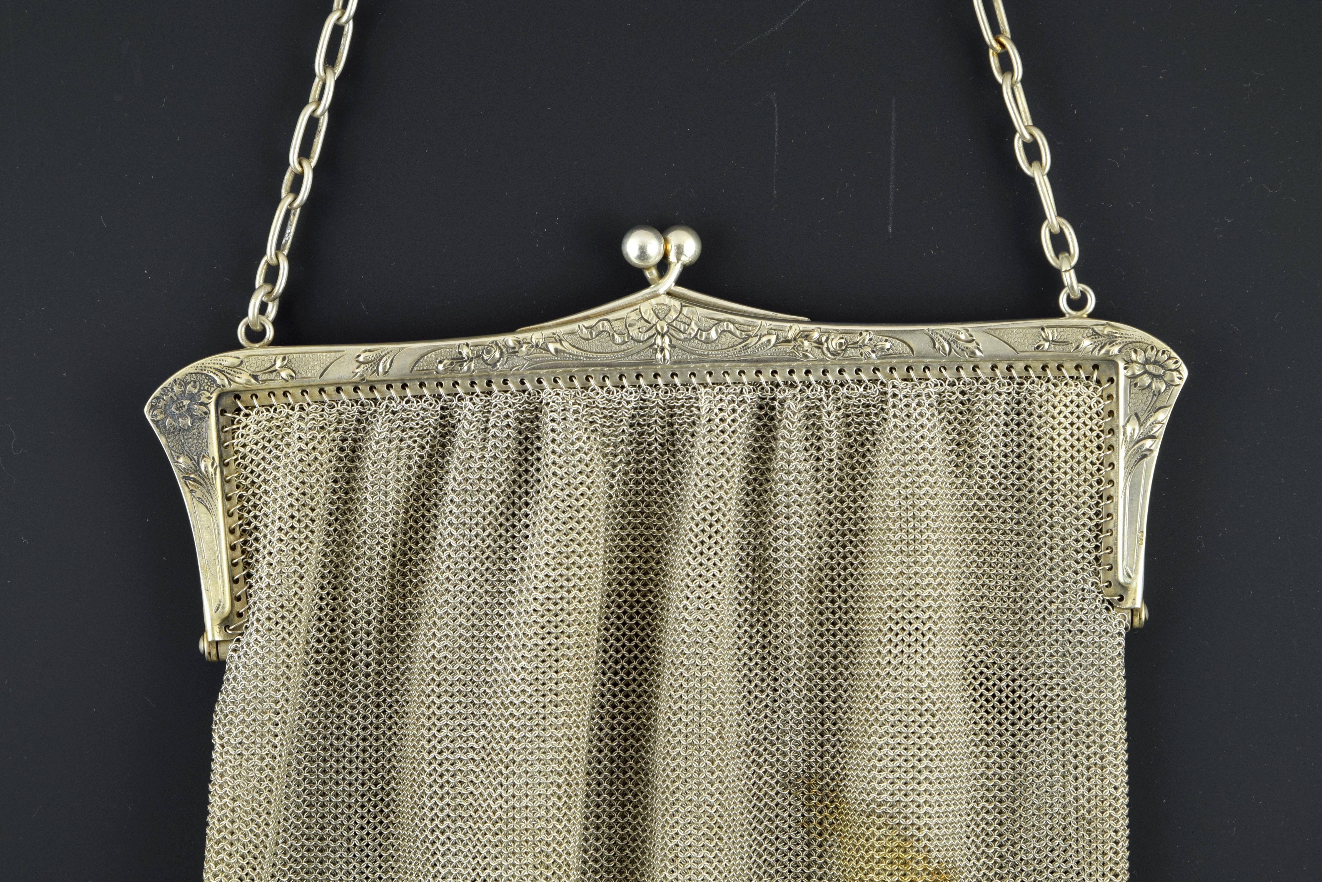 Silver mesh bag in its color decorated with triangular elements on the bottom that has a smooth closure by hinges and a chain of alternating long and short links. This type of pieces were very frequent in the 19th century, as a luxury element and a