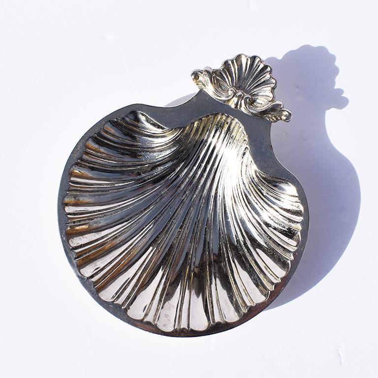 Metal Grotto style shell dish in a silver hue. Standing on three rounded footed feet, this dish elevates slightly off of where it sits.

In a silver metal, this piece is shaped into a scalloped seashell. Ridges are gracefully cut into it’s body,