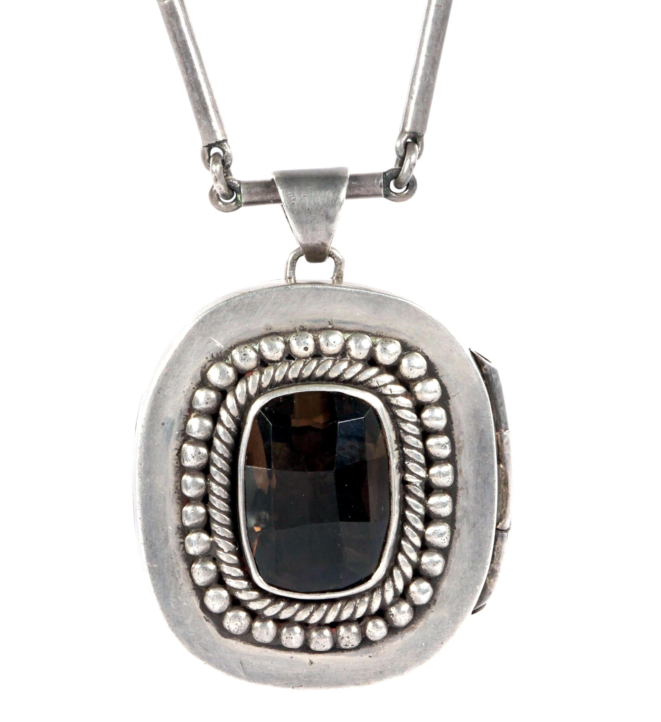 A beautiful Mexican sterling silver necklace made by Taxco silversmith Antonio Pineda post 1956. The articulated chain links carries a locket pendant with a smoky quartz cabochon. Fully marked inside of the locket with silver content of 0.97.