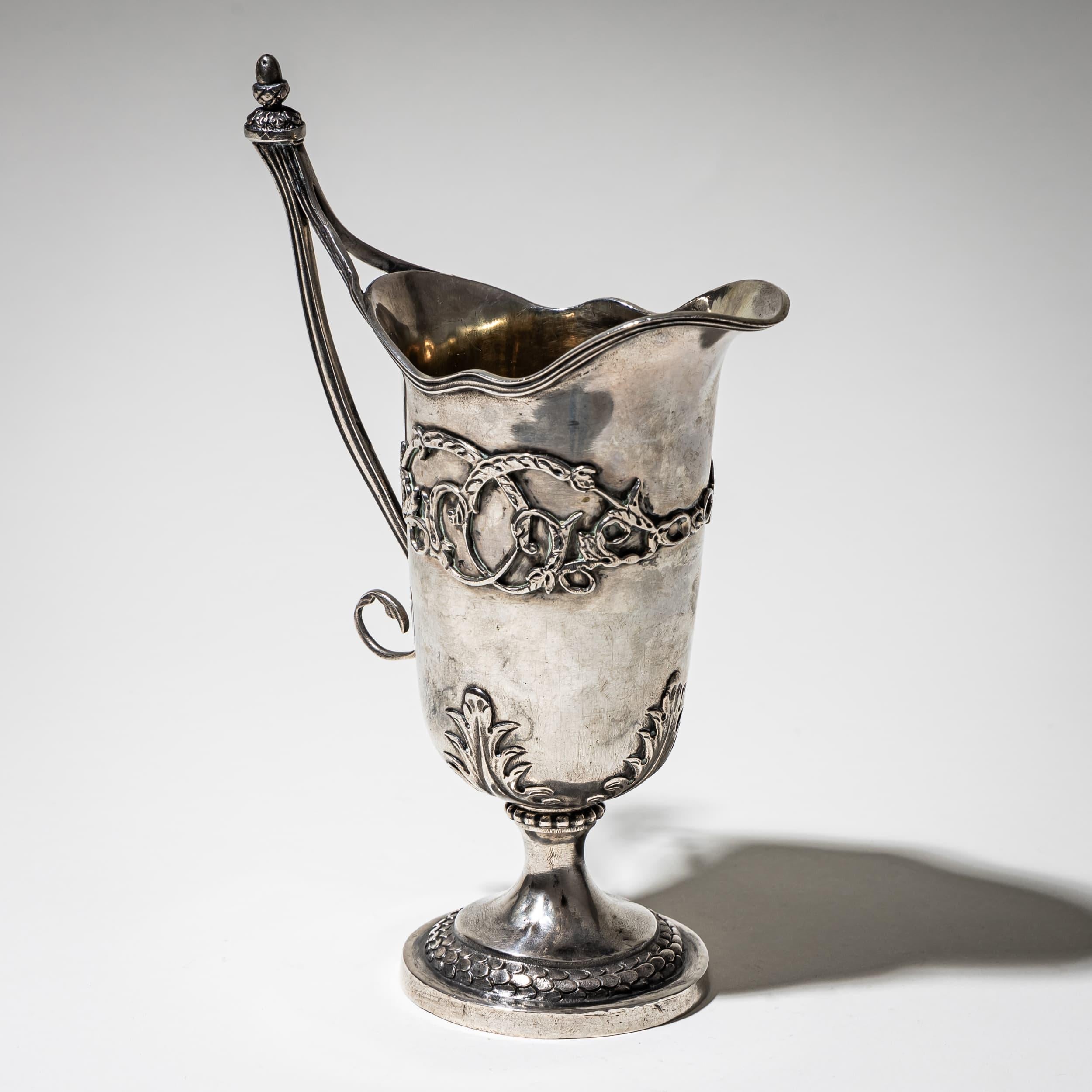 Fine silver milk jug with a scalloped rim and tapered body, adorned with applied rocaille decoration. The long, gracefully curved handle adds elegance. Hallmarked at the base with maker’s mark CWS. Weight: 266 g