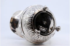 Silver milk jug with chiseled florals and claw-foot base