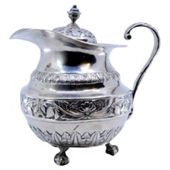 Silver milk jug with chiseled florals and claw-foot base
