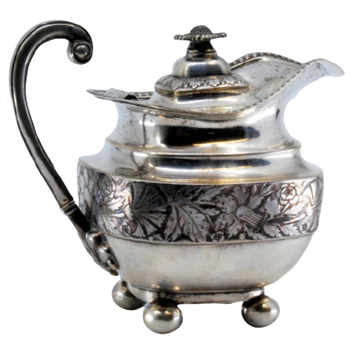 Silver milk jug with chiseled florals, missing handle, and knobbed lid