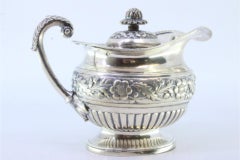 Silver milk jug with embossed florals, rim friezes, and acanthus-leaf handle