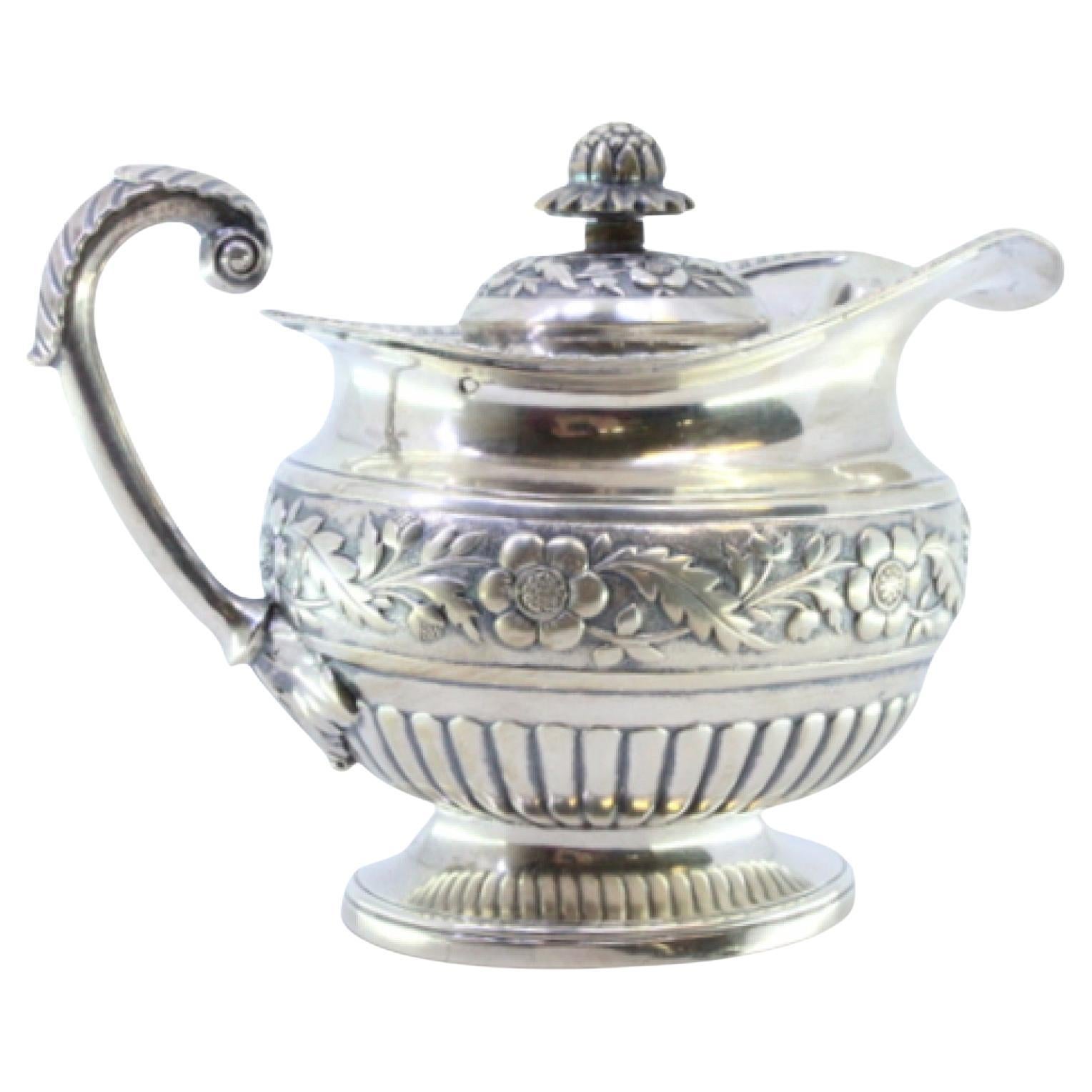 Silver milk jug with embossed florals, rim friezes, and acanthus-leaf handle