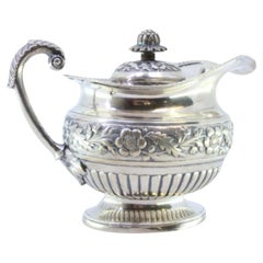 Silver milk jug with embossed florals, rim friezes, and acanthus-leaf handle