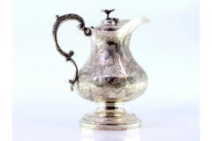 Silver milk jug with floral motifs, engraved birds, and flower-shaped knob