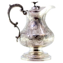 Silver milk jug with floral motifs, engraved birds, and flower-shaped knob