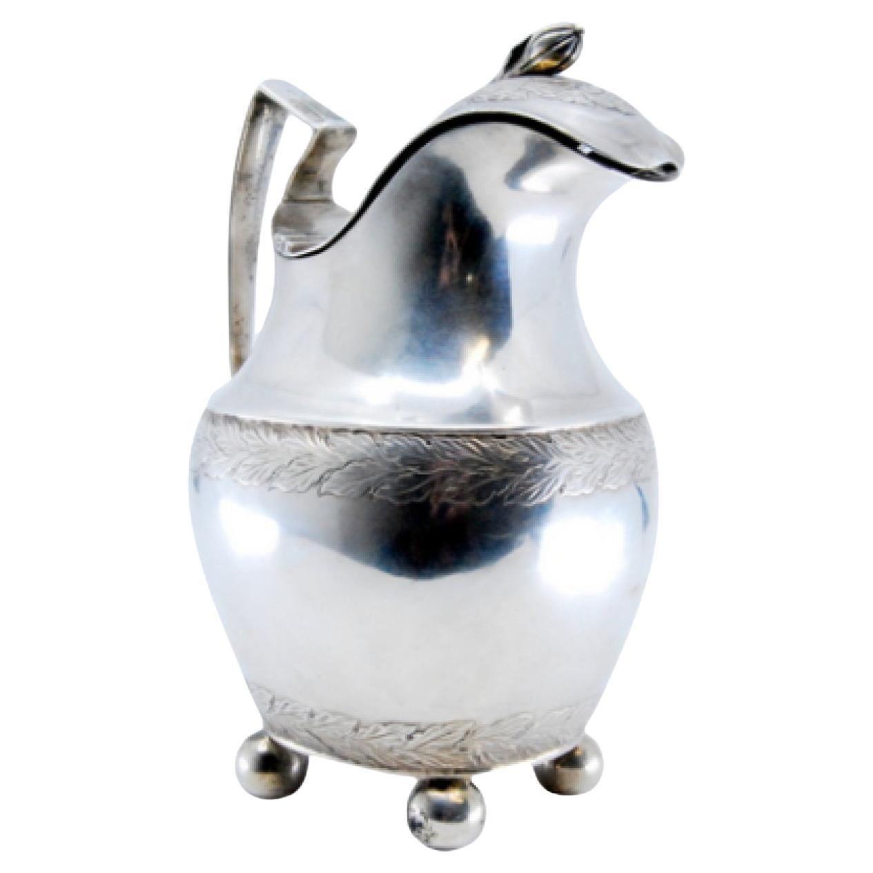 Silver milk jug with friezed lid, knob, on four ball feet in D. Maria style