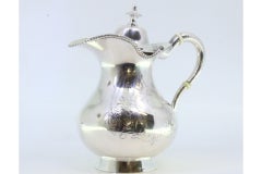 Silver milk jug with plant engravings, monogram card, and knobbed lid