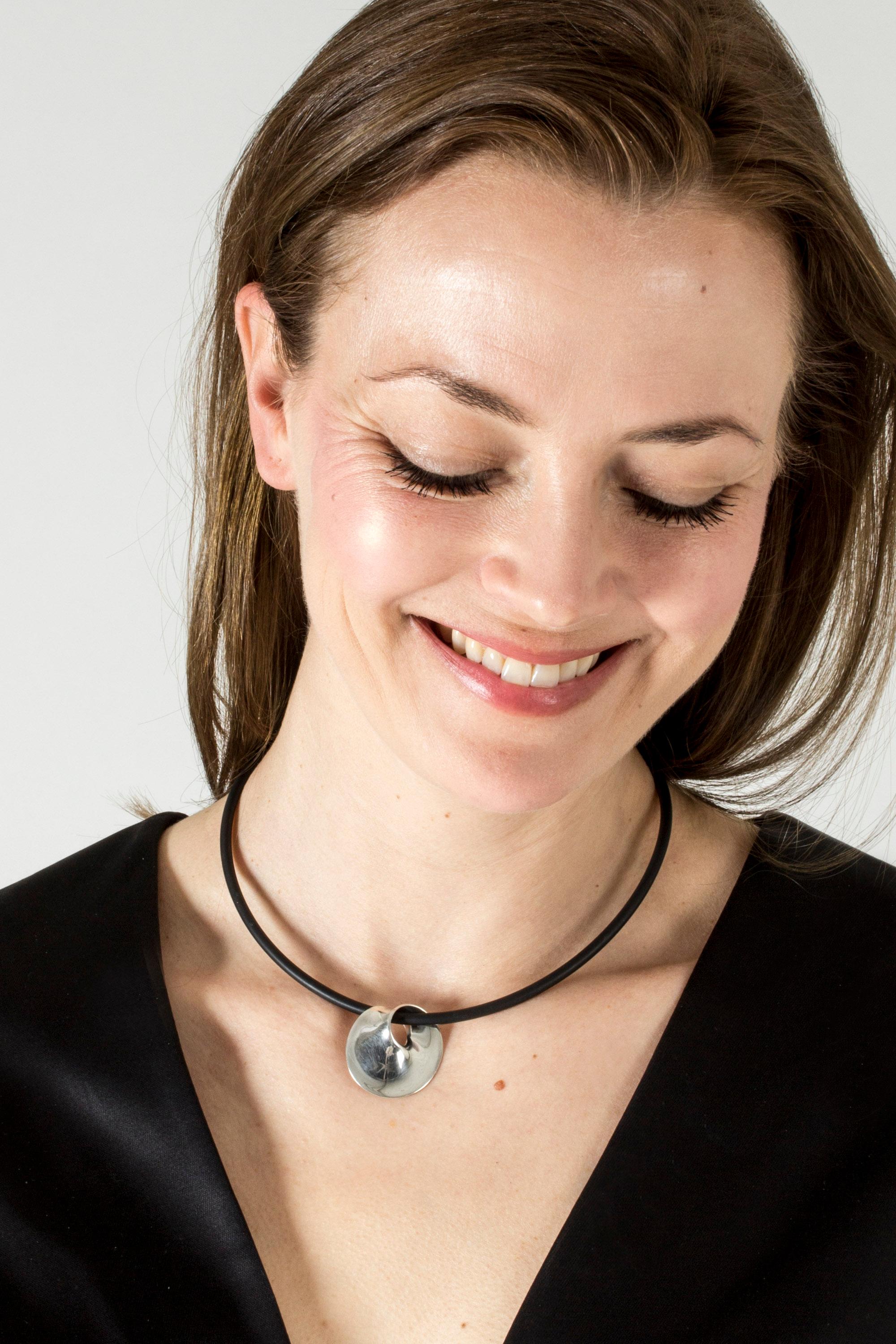 Beautiful “Möbius” pendant by Torun Bülow-Hübe, on a cool rubber neckring. Torun’s classic design is inspired by geometrical forms and expresses an eye-catching harmony. Timeless design that looks great with a casual look.