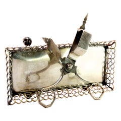 Silver morrões tray 
scissors w/ a wire rack 
resting on four claw-shaped feet