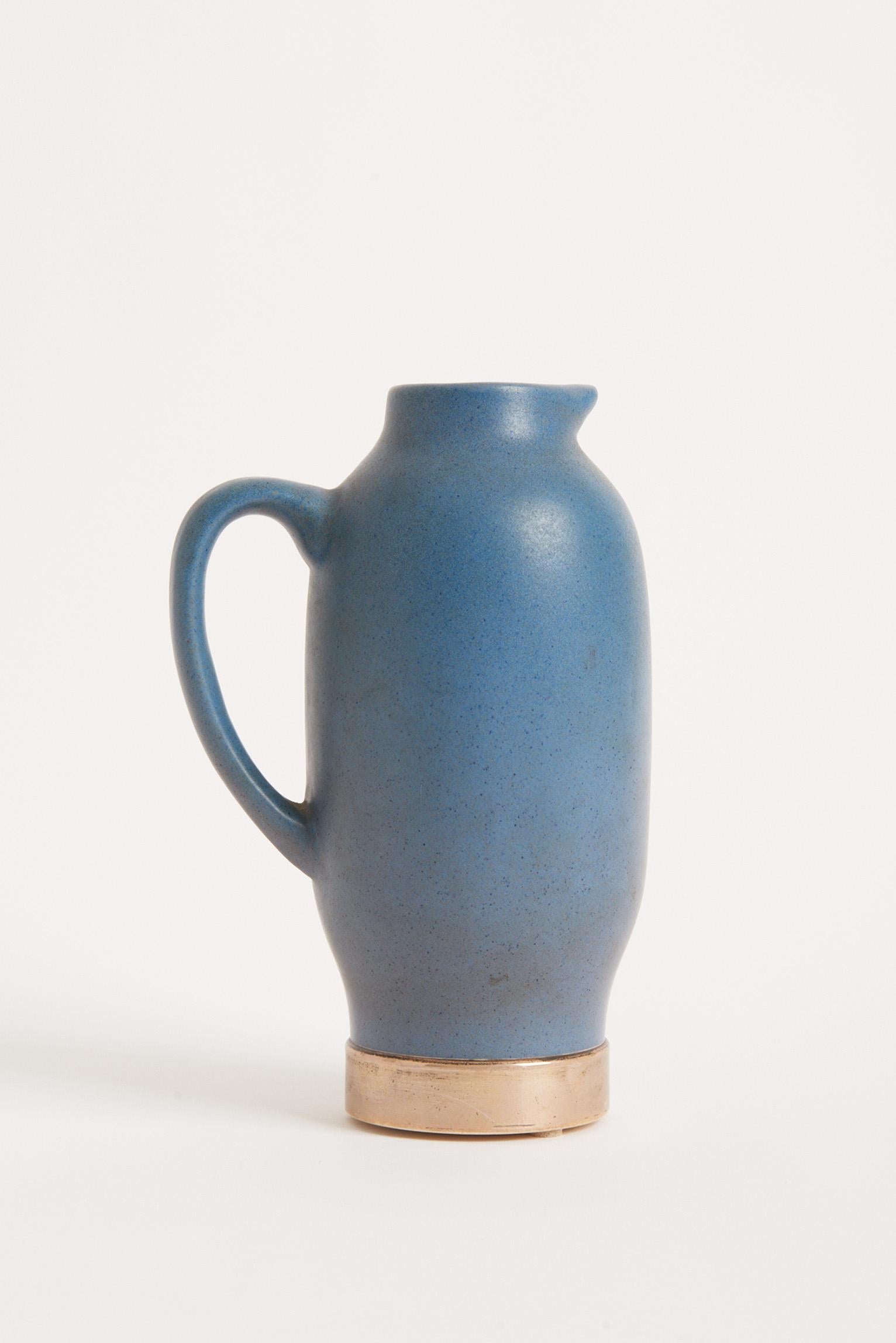 A mottled blue stoneware jug, on a solid silver base.
Bearing two Spanish silver hallmarks: the five-point star silver fineness mark for 915/1000 purity (plata de ley) and the city of Barcelona assay office mark. Also bearing the ceramicist