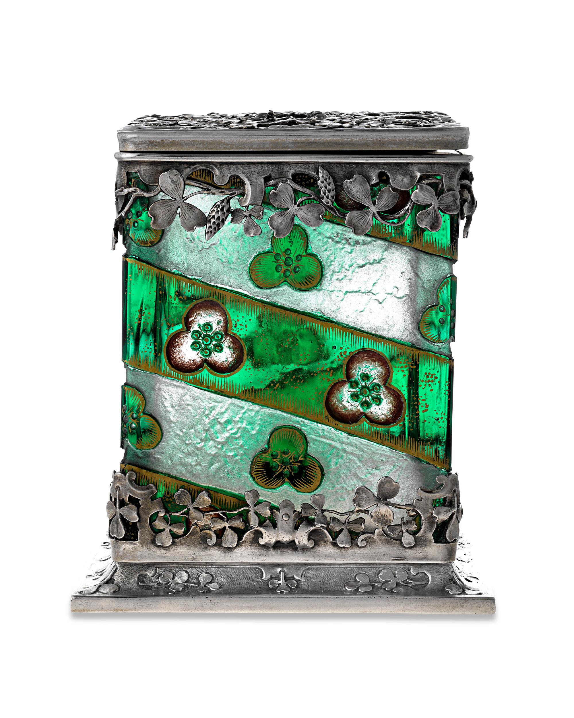 Ce ravissant coffret en verre vert et argent de la célèbre société française de verrerie d'art Daum évoque la luxuriance verdoyante d'un jardin d'été. Des trèfles et des vignes en argent finement détaillés entourent le verre vert riche de cette