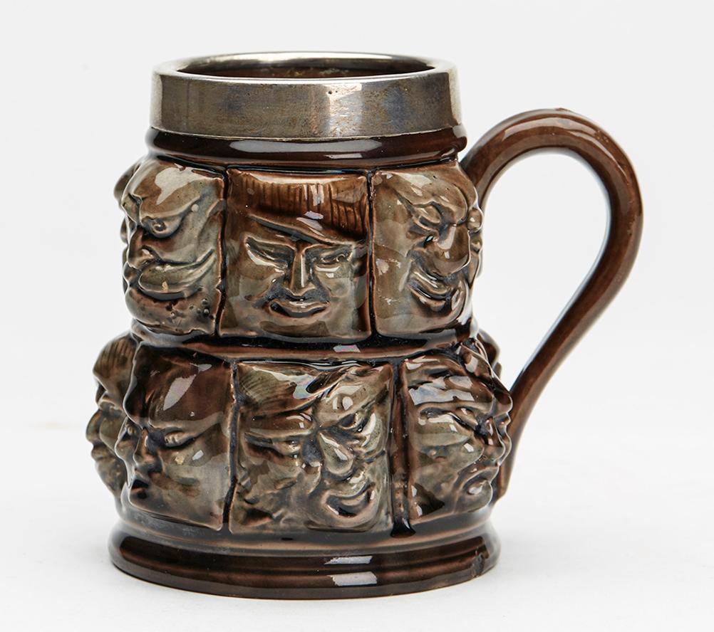 Late 19th Century Silver Mounted Thirteen Grotesque Faces Molded Glazed Pottery Mug For Sale