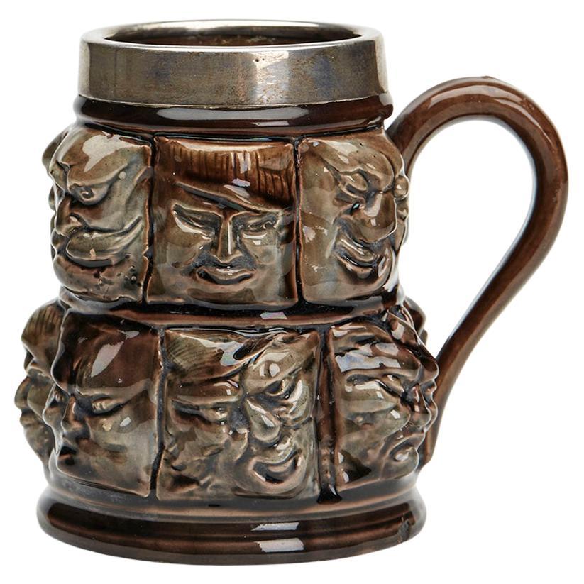 Silver Mounted Thirteen Grotesque Faces Molded Glazed Pottery Mug For Sale