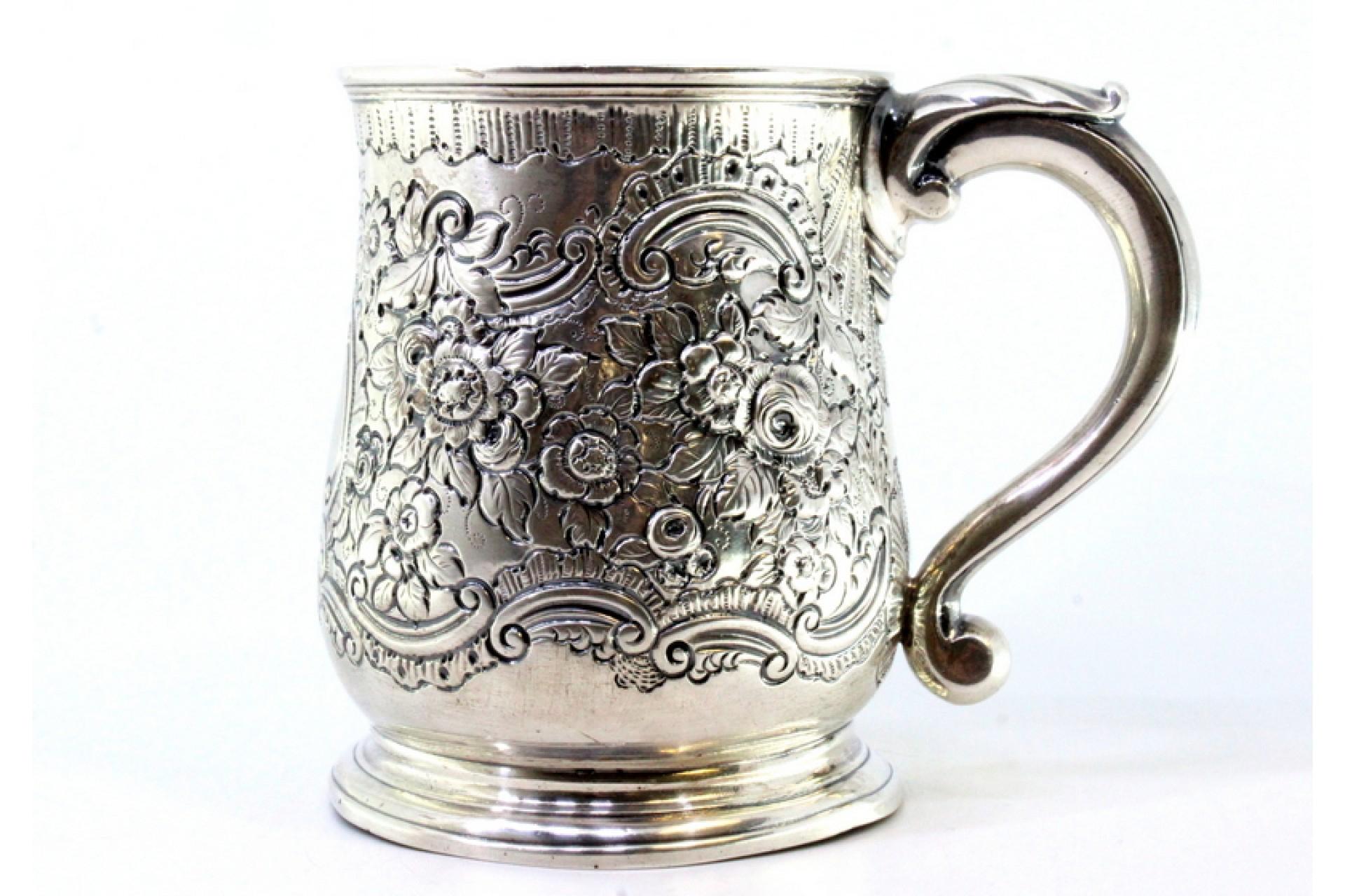 Descripción: Taza de plata con motivos florales revelados que rodean una tarjeta con monograma y asa repujada. Metal: Silver. Origen: Inglés. Marca: ilegible. Peso: 350,99 gramos. Dimensiones: 13 cm x 11,3 cm. Contenido: 925/1000. Marca de ensayo: