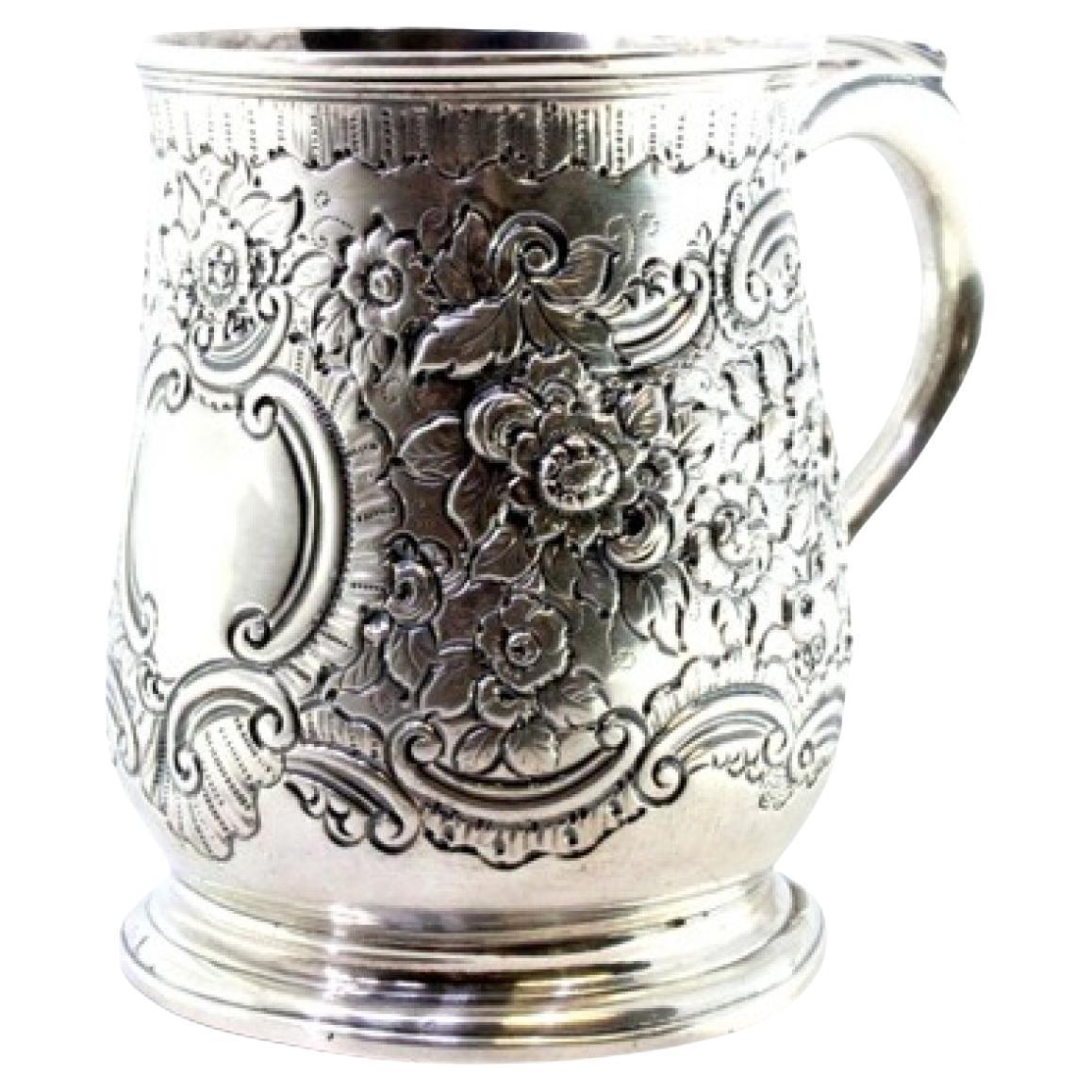 Silver mug with floral reliefs, monogram cartouche and embossed handle