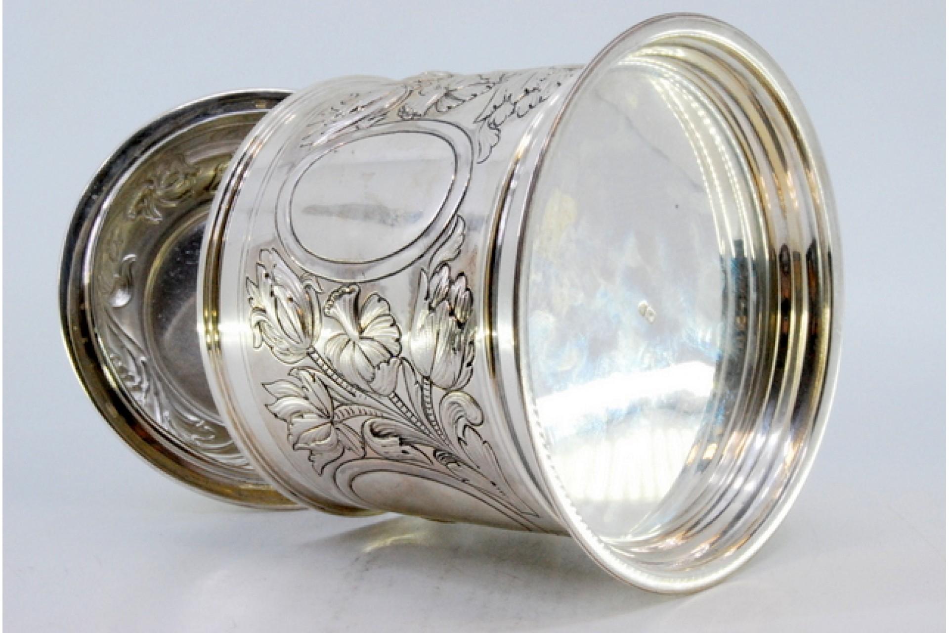 Description: Silver mug with relief floral motifs surrounding monogram cards. . Metal: Silver. Origin: Portuguese. Brand: open wing eagle. Weight: 739.98 grams. Dimensions: 13.5x13.3cm. Content: 925/1000. Assay Mark: Yes, between 1985 and 2021.