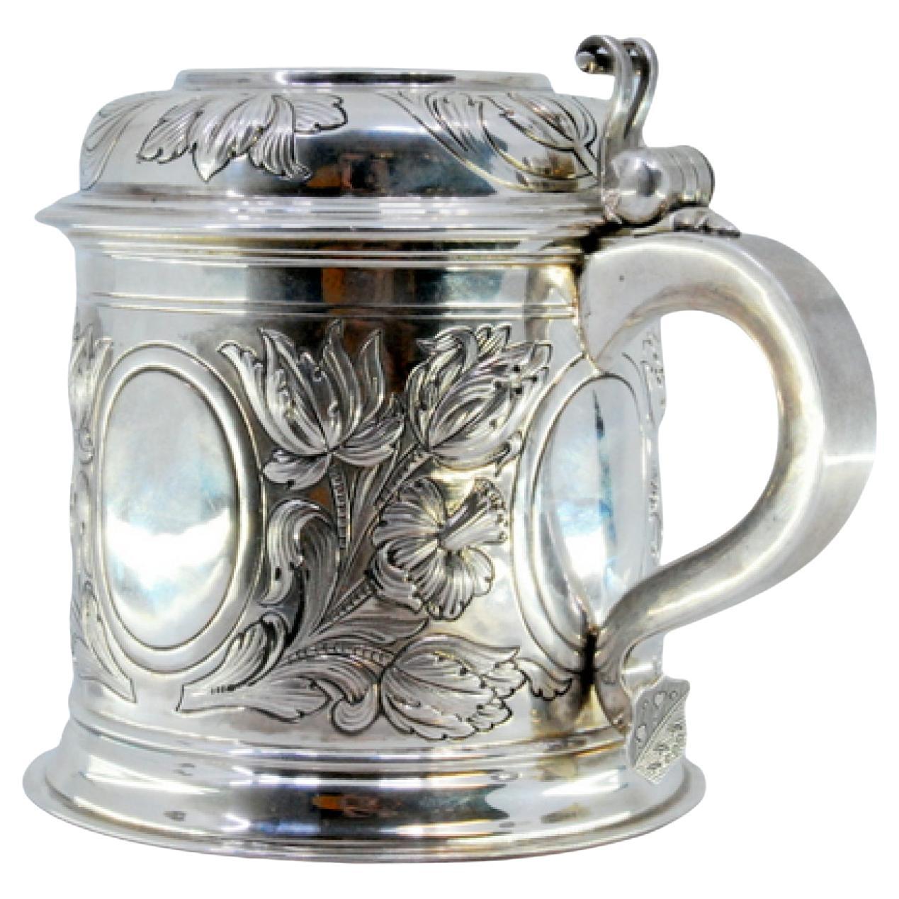 Silver mug with relief floral motifs surrounding monogram cards